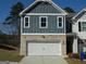 Two-story home with vertical siding, a brick base, a two-car garage, and manicured front yard at 7484 Knoll Hollow Rd, Lithonia, GA 30058