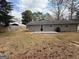 View of the backyard featuring a charming, single-story home with a small patio and a grassy lawn at 2987 Landmark Se Dr, Conyers, GA 30094