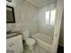 Well-lit bathroom with white marble-like tiling, a granite-like sink, and a shower/tub combo at 1380 Margarette Dr, Decatur, GA 30035