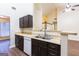 Bright kitchen with dark wood cabinets, stainless steel sink, white appliances, and a view of the staircase at 3821 Rex Mill Sq, Rex, GA 30273