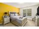 Bright bedroom featuring a king-sized bed, yellow accent wall, and natural light from a window at 11882 Fuller St, Hampton, GA 30228