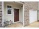 Close-up of the front porch of a brick townhome with a dark wood door and chair, creating a welcoming entrance at 11882 Fuller St, Hampton, GA 30228