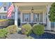 Inviting front porch with stone accents, shuttered windows, and cozy seating, enhanced by lush landscaping and the American flag at 341 Beaumont Farms Dr, Sharpsburg, GA 30277