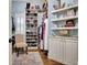 Organized walk-in closet with custom shelving, shoe racks, hanging rods, and decorative shelves above white cabinets at 341 Beaumont Farms Dr, Sharpsburg, GA 30277