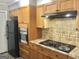 Close-up view of a modern kitchen featuring wood cabinets, a black cooktop, and built-in oven at 4572 Sahara Sw Dr, Atlanta, GA 30331