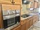 Close-up of a kitchen featuring a stainless steel oven, wood cabinetry, and tiled backsplash at 4572 Sahara Sw Dr, Atlanta, GA 30331