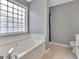 Modern bathroom with glass block window, soaking tub, and neutral paint at 306 Turtle Pointe Dr, Carrollton, GA 30116