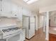 Updated kitchen with white cabinets, granite countertops, white appliances, and adjacent shelving at 290 Rocky Branch Dr, Mcdonough, GA 30252