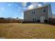 Backyard view featuring a tidy lawn, young tree, and the rear of the house showcasing multiple windows at 443 Faulkner St, Stockbridge, GA 30281