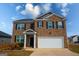 Two-story brick home featuring a two-car garage, black shutters, and a well-maintained front yard at 443 Faulkner St, Stockbridge, GA 30281