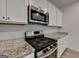 Close up of modern kitchen with stainless steel gas range and white cabinets at 1659 Hay Patch Ln, Loganville, GA 30052