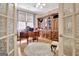 Bright home office with wood floors, built-in shelving, desk, large window, and glass paneled doors at 221 Collierstown Way, Peachtree City, GA 30269