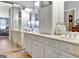 Main bathroom featuring double sinks, white cabinets, large mirrors, and a view into the bedroom at 221 Collierstown Way, Peachtree City, GA 30269