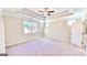 Spacious bedroom featuring a tray ceiling, ceiling fan, and large window at 2455 Westlington Cir, Cumming, GA 30040