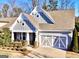 Charming home exterior with light-colored siding, decorative garage doors, and manicured landscaping at 2455 Westlington Cir, Cumming, GA 30040