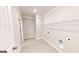 Tiled laundry room with white walls, base trim and hanging shelf with rod at 2455 Westlington Cir, Cumming, GA 30040