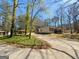 View of a home featuring a long driveway flanked by lush greenery and mature trees, providing a serene setting at 127 Circle H Rd, Sharpsburg, GA 30277