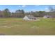 Exterior view of the home with a spacious backyard surrounded by a green meadow and trees at 196 Old Highway 92, Fayetteville, GA 30215