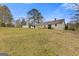 Large grassy backyard showcasing the back of the home with a new wooden deck and mature trees at 1312 Milstead Ne Ave, Conyers, GA 30012