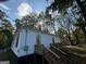 Exterior of home with wooden stairs and porch nestled among mature trees at 1 Maple St, Porterdale, GA 30014