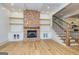 Spacious living room featuring a brick fireplace, custom built-ins, and hardwood floors, connecting to the kitchen at 721 Wedowee St, Bowdon, GA 30108
