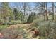 Serene backyard featuring a stone pathway, lush greenery, and mature trees at 300 The Enclave, Peachtree City, GA 30269