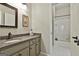 Bright bathroom featuring a vanity with granite counters, framed mirror, and a tiled shower/bath combo behind an open door at 300 The Enclave, Peachtree City, GA 30269