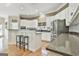 Open-concept kitchen with a bar, stainless steel appliances, white cabinetry, and a neutral color palette at 300 The Enclave, Peachtree City, GA 30269