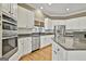 A kitchen with a stainless steel dishwasher and oven, complemented by white cabinets and wood floors at 300 The Enclave, Peachtree City, GA 30269