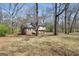 View of the rear of a house with brick and vinyl siding, surrounded by mature trees and a lawn covered in leaves at 40 Derby Country Dr, Ellenwood, GA 30294