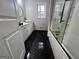 Modern bathroom with black and white color scheme, a glass enclosed tub, and a marble countertop at 127 Brookwood Estates Trl, Stockbridge, GA 30281