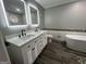 Elegant bathroom featuring a dual sink vanity, standalone tub, and illuminated mirrors at 127 Brookwood Estates Trl, Stockbridge, GA 30281