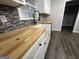 Well-lit kitchen with sleek backsplash, butcher block counters, a farmhouse sink, and gray flooring at 127 Brookwood Estates Trl, Stockbridge, GA 30281