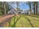 View of a grey two-story home with stairs and a deck surrounded by a grassy yard and lush trees at 6192 Holiday Blvd, Forest Park, GA 30297