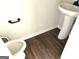 Half bath includes dark wood floors, pedestal sink and white toilet at 413 Samara Ct, Fairburn, GA 30213