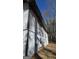 Exterior perspective shows home's siding, dark trim, and foundation with ladder, framed by tall trees and blue sky at 3189 Fern Ridge Ne Dr, Conyers, GA 30013