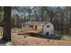Charming home exterior featuring a wooden deck and a red front door, surrounded by a lush, wooded landscape at 3189 Fern Ridge Ne Dr, Conyers, GA 30013