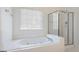 Bright bathroom features a glass enclosed shower and a soaking tub next to a window at 1491 Hada Ln, Lawrenceville, GA 30044