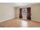 Empty bedroom showcasing hardwood floors and a window with maroon patterned curtains at 1100 Parkside Ln, Mcdonough, GA 30253