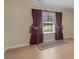 Empty bedroom showcasing hardwood floors and a window with maroon patterned curtains at 1100 Parkside Ln, Mcdonough, GA 30253