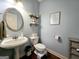 Charming powder room with pedestal sink, wood floors, and decorative shelving at 1441 Henderson Ridge Ln, Loganville, GA 30052