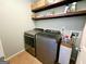 Functional laundry room equipped with modern appliances, storage shelves, and tiled flooring at 1441 Henderson Ridge Ln, Loganville, GA 30052