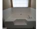 Bathroom featuring a large soaking tub with tile surround and a window for natural light at 180 Sunderland Cir, Fayetteville, GA 30215