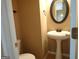 Cozy powder room featuring a pedestal sink, decorative mirror and a neutral color palette at 180 Sunderland Cir, Fayetteville, GA 30215
