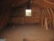 Unfinished attic space featuring exposed wooden beams, a window for natural light, and built-in shelving at 2102 Mulkey Sw Rd, Marietta, GA 30008