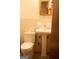 Bathroom featuring a pedestal sink, a toilet, a mirror, and neutral tile floors at 2102 Mulkey Sw Rd, Marietta, GA 30008
