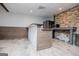 Basement kitchenette with stone accent wall, microwave, bar and light colored floors at 2304 Larchmont Ct, Villa Rica, GA 30180