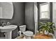 Stylish powder room with dark walls, vessel sink, round mirror, and a charming plant, maximizing its appeal at 734 Lanarck Way, Peachtree City, GA 30269
