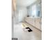 Bright bathroom featuring double vanity with white cabinets and modern rectangular rug accenting the light tile floor at 734 Lanarck Way, Peachtree City, GA 30269