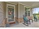 Cozy covered porch with rocking chairs, a wreath on the front door and beautiful flowering plants at 734 Lanarck Way, Peachtree City, GA 30269
